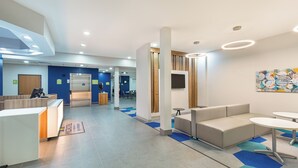 A modern reception area with a reception desk, seating area, and a large artwork on the wall. - Microtel Inn and Suites by Wyndham Columbus North (Columbus)