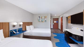 A hotel room with two beds, a desk with a computer, a flat-screen TV, and a microwave.
