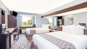A hotel room with two beds, a desk, a TV, and a large window with curtains. - Microtel Inn and Suites by Wyndham Columbus North (Columbus)