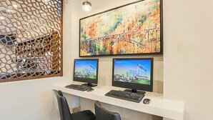 Un espacio de oficina moderno con dos monitores, un escritorio blanco, sillas negras y un cuadro abstracto grande en la pared.