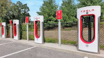 A row of Tesla electric vehicle charging stations in a parking lot.