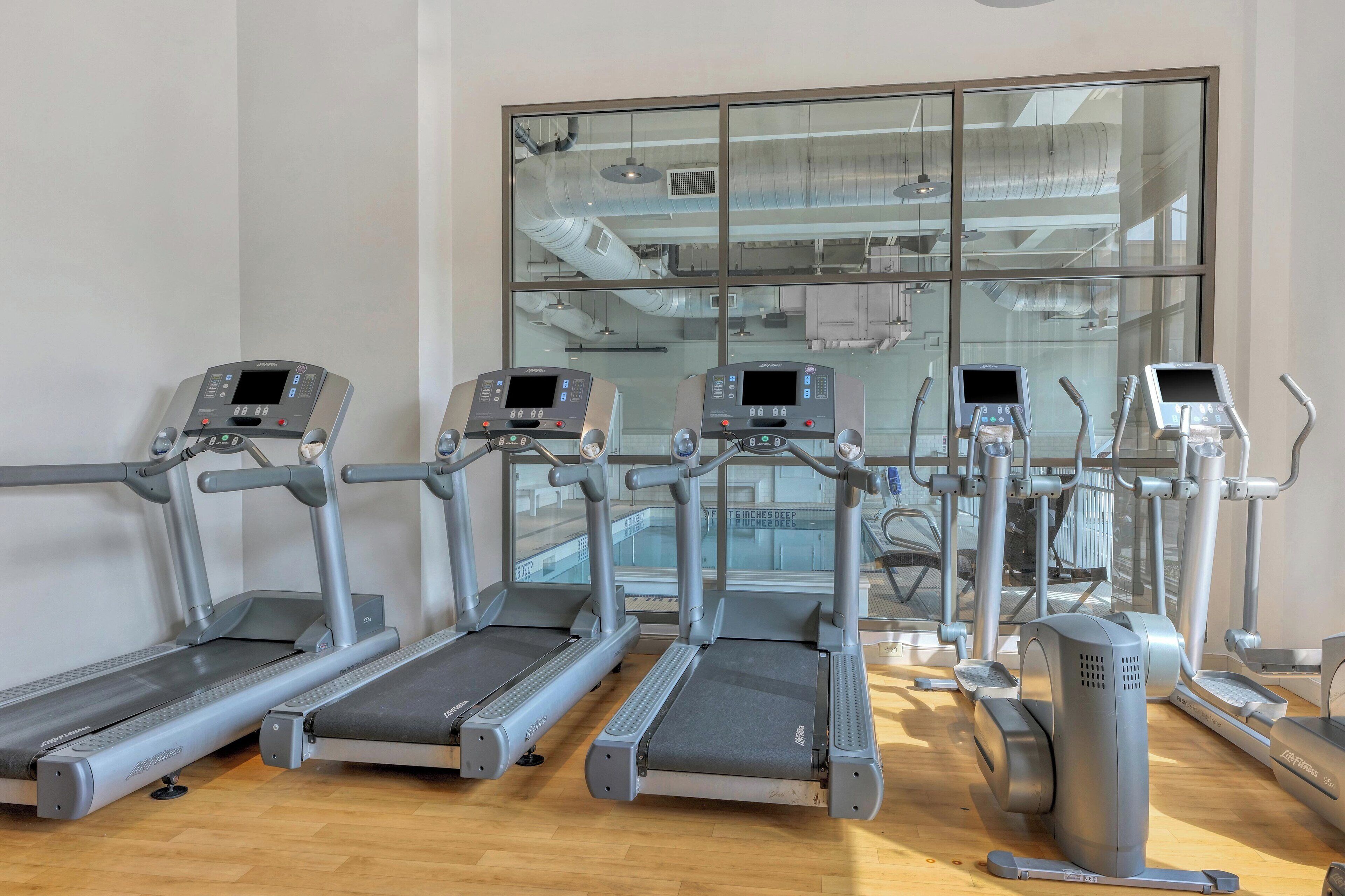 Un gimnasio con cintas de correr, elípticas y una bicicleta estática.