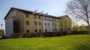 A Holiday Inn Express building with multiple flags, including the UK flag, and a well-maintained lawn in front.