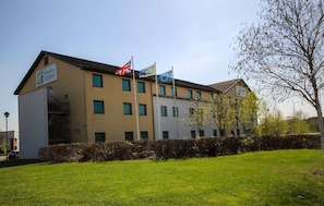A Holiday Inn Express building with multiple flags, including the UK flag, and a well-maintained lawn in front.