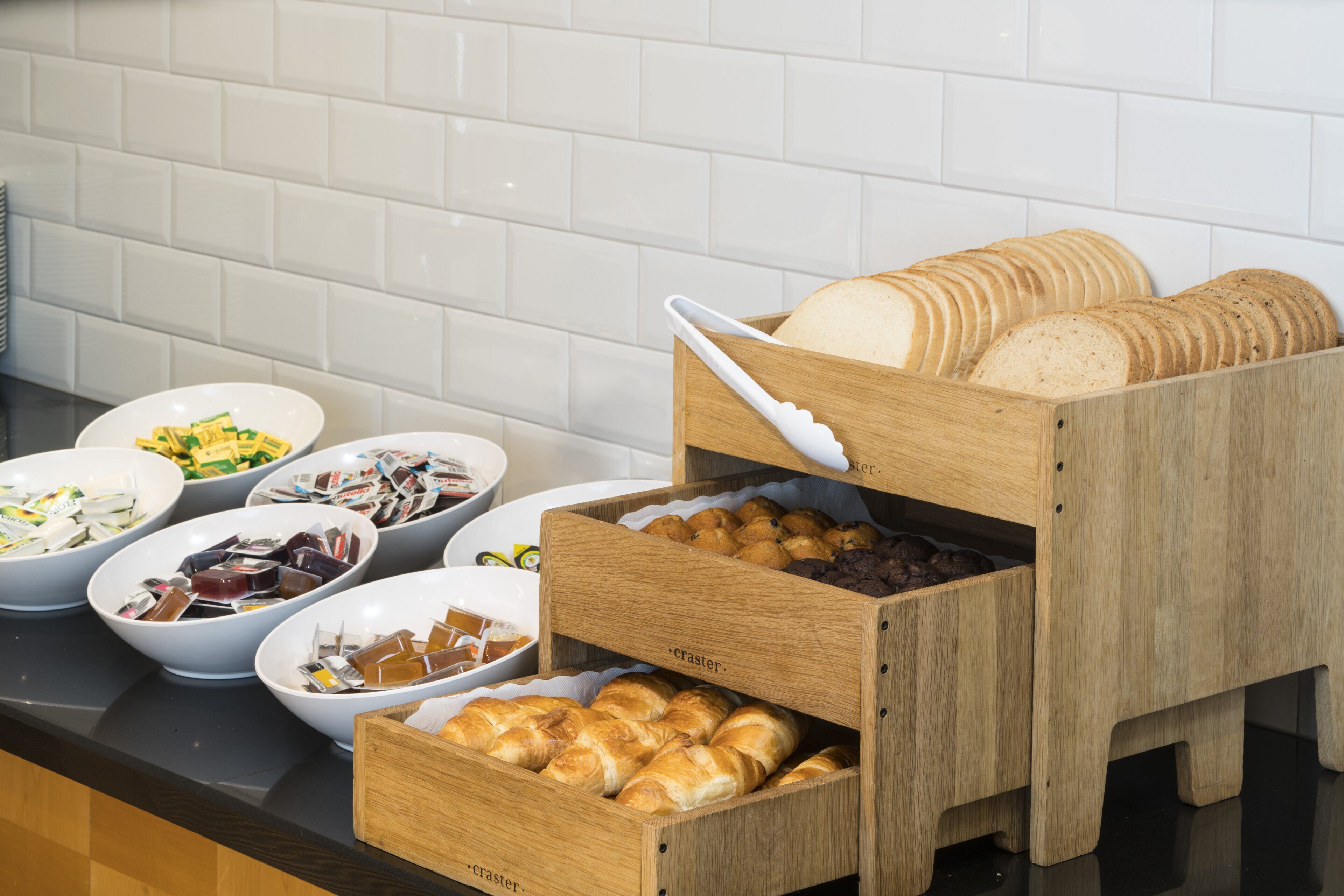 A breakfast buffet with bread, pastries, and assorted spreads.