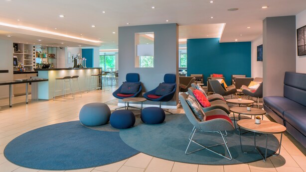 A modern lounge area with seating, a bar, and a view of the outdoors.