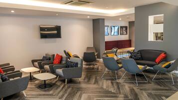 A modern lounge area with sofas, chairs, and a flat-screen TV mounted on the wall.