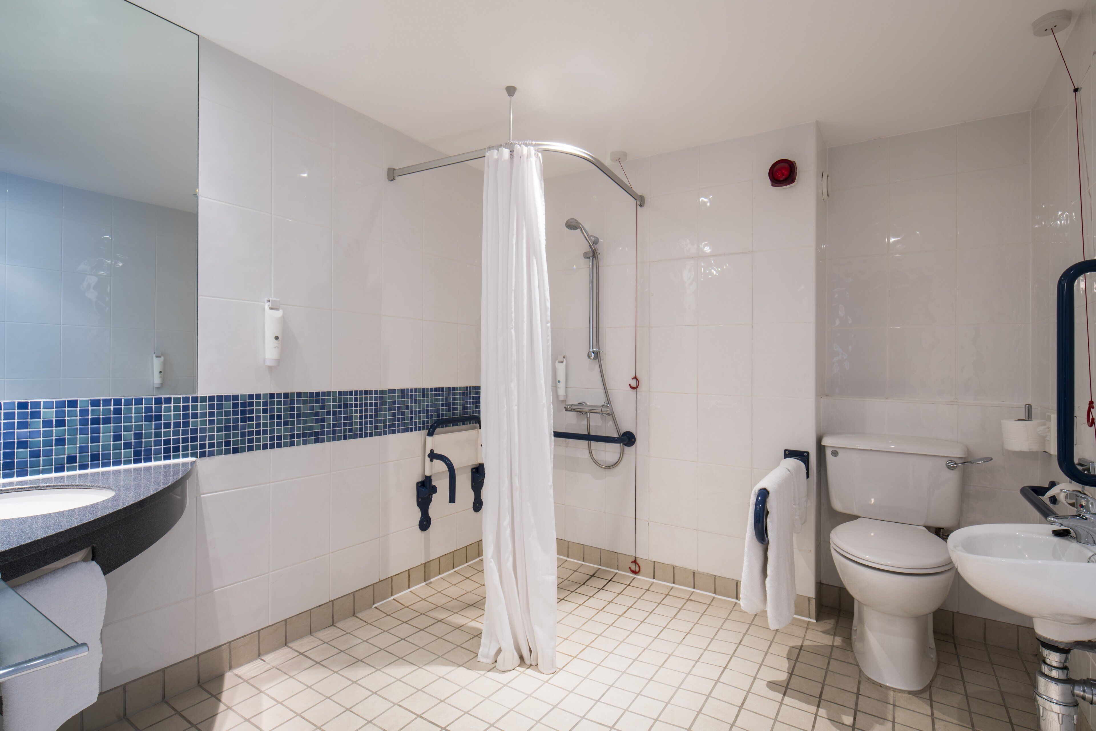 Un baño moderno con ducha, inodoro, lavamanos y espejo.