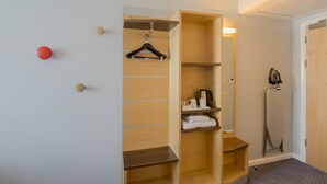 A walk-in closet with wooden shelves, a hanging rack, and a compact iron.