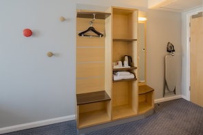 A walk-in closet with wooden shelves, a hanging rack, and a compact iron.