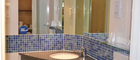 A bathroom with a sink, mirror, and blue-tiled walls.