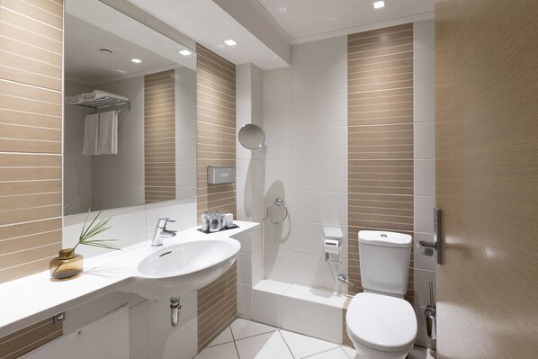 A modern bathroom with a sink, mirror, toilet, and shower.