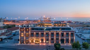 Un hôtel doté d’une entrée imposante et offrant une vue sur le port et la mer en arrière-plan.
