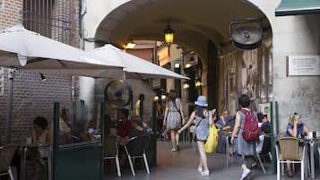 An outdoor café with tables and chairs, a brick wall, and a green awning.