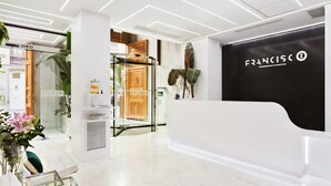 A modern reception area with a black and white color scheme, a sign reading "FRANCISCO," and a glass door leading to a room with a wooden door. - Hotel Francisco I (Madrid)