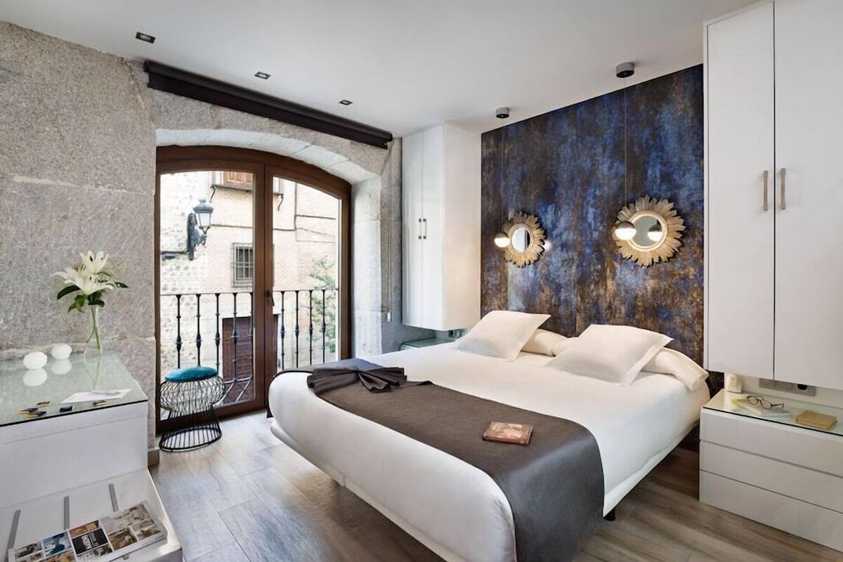 A modern bedroom with a bed, bedside tables, a wardrobe, and a view of the outside.