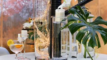 Una mesa con jarrones de vidrio transparente que contienen velas y una planta, y una copa de cóctel con una rodaja de limón.