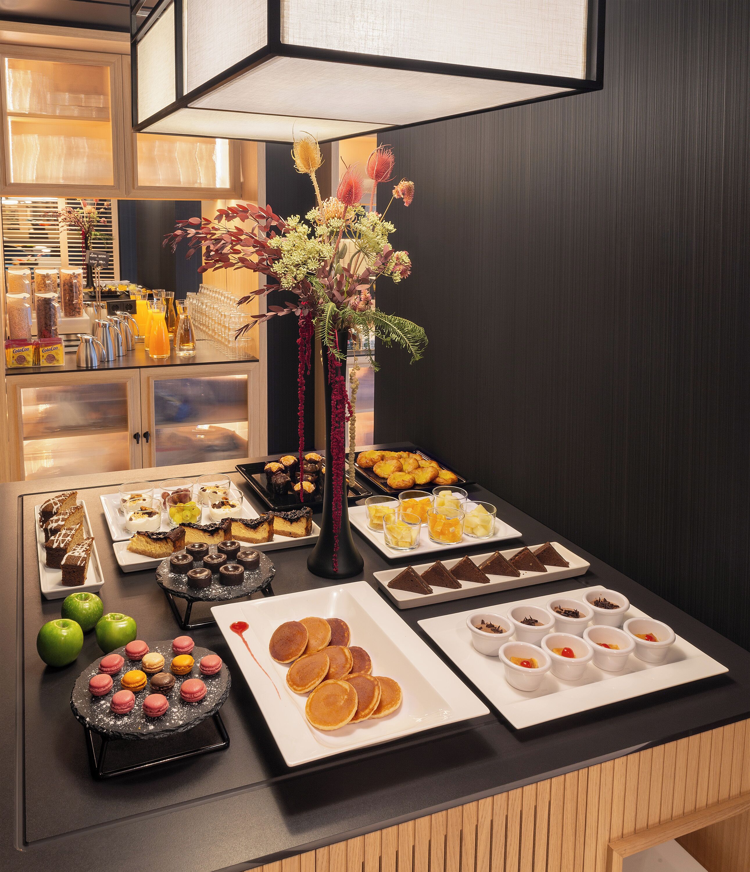 A breakfast buffet with various food items and a decorative vase.