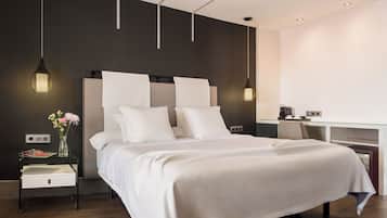 Ein modernes Hotelzimmer mit einem großen Bett, einem Nachttisch und einem Schreibtisch mit Stuhl.