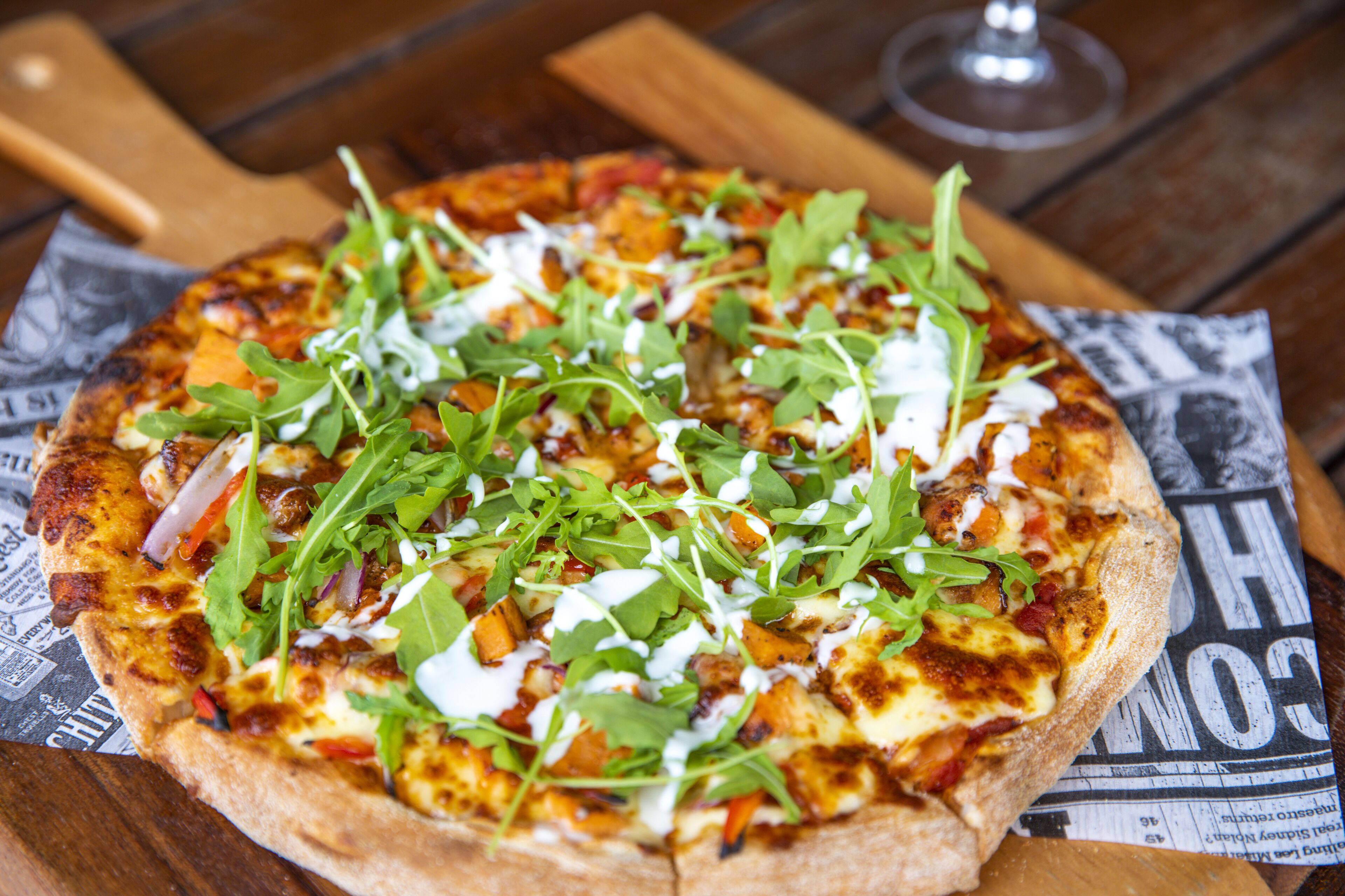 A pizza with various toppings on a wooden surface.