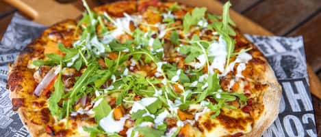 A pizza with various toppings on a wooden surface.
