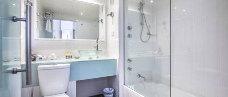 Un baño moderno con ducha envuelta en vidrio, inodoro blanco y lavamanos de vidrio.