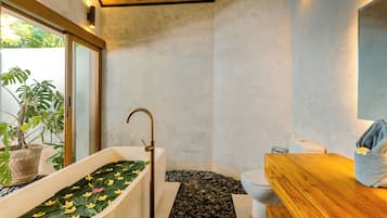 A modern bathroom with a freestanding bathtub, a wooden vanity, and a toilet.