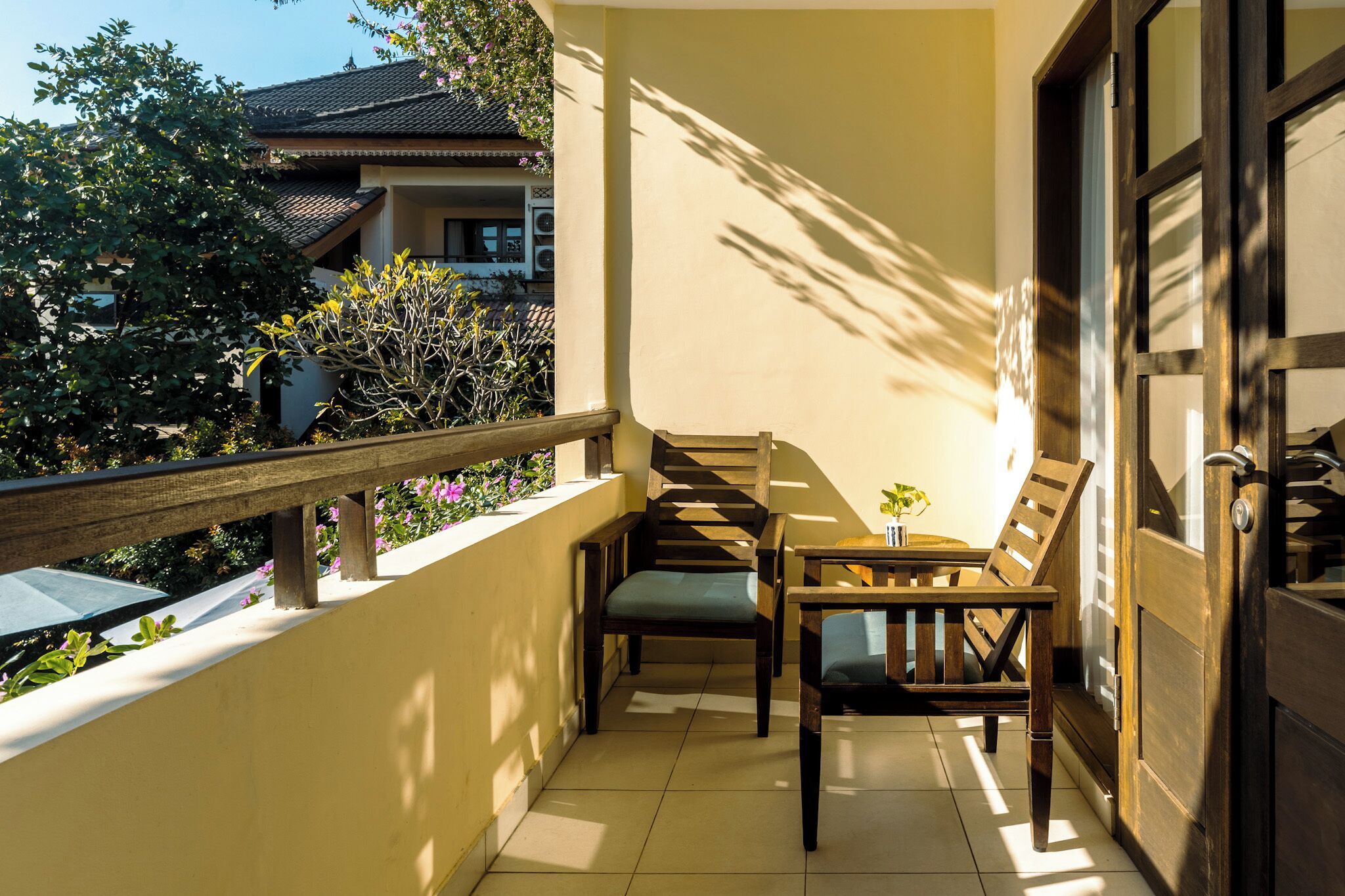 A balcony with a wooden railing, a small table, and two chairs.