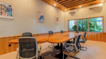 A conference room with a long wooden table, six chairs, and framed artwork on the walls.