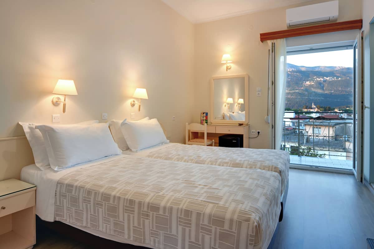 Een hotelkamer met twee bedden, een groot raam met uitzicht op bergen en een balkon.