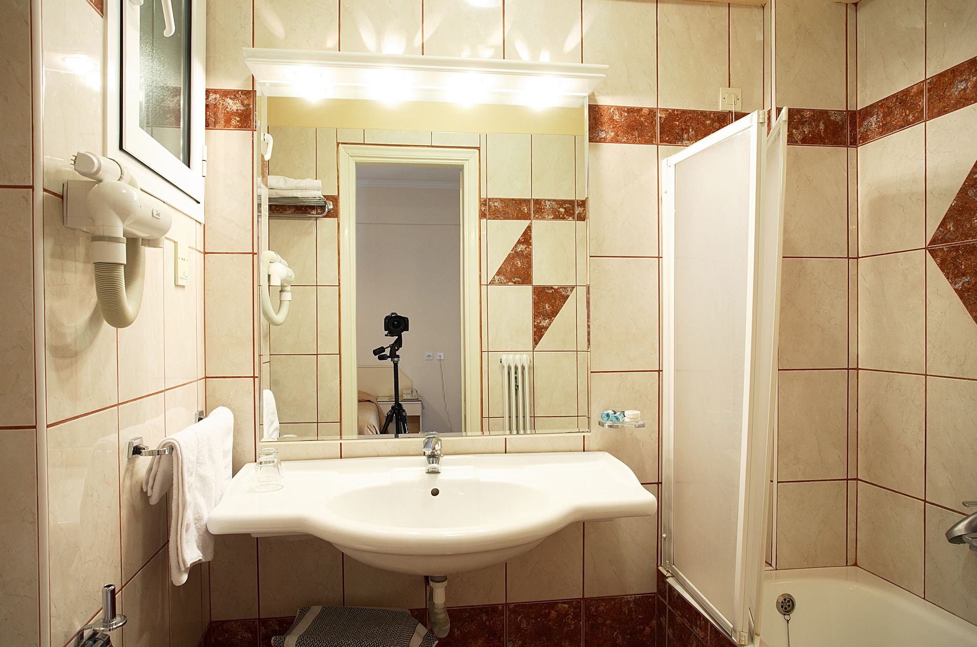 A bathroom with a sink, mirror, towel rack, and shower.