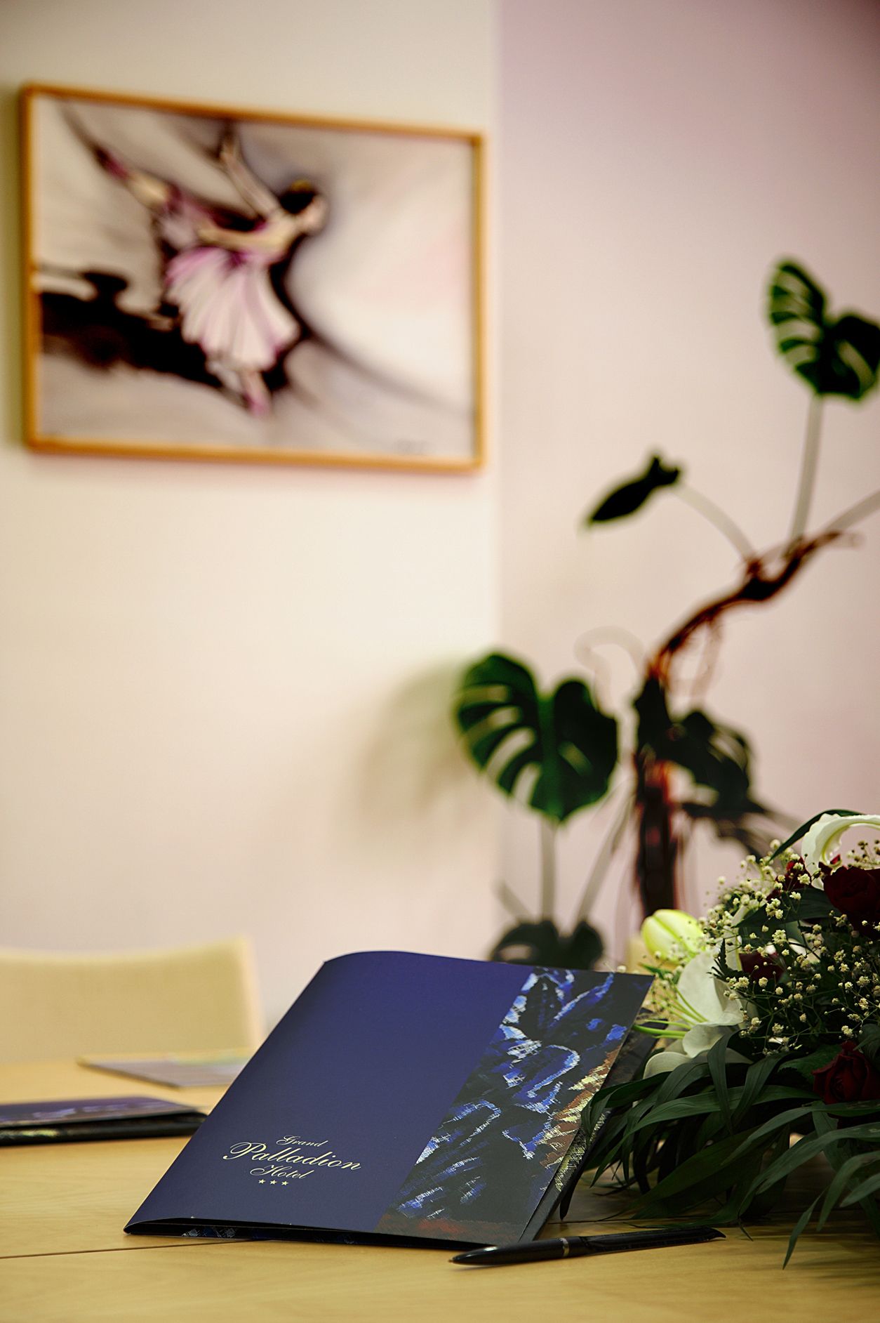 A desk with a laptop, a bouquet of flowers, and a potted plant.
