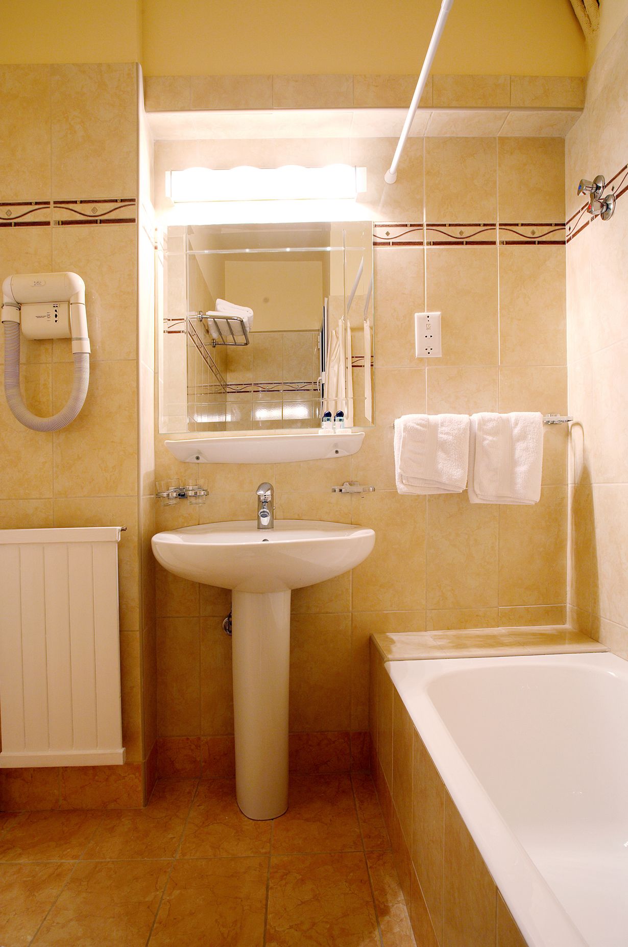 A bathroom with a sink, mirror, towel rack, and bathtub.