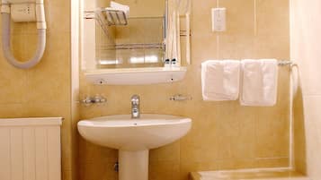 A bathroom with a sink, mirror, towel rack, and bathtub.