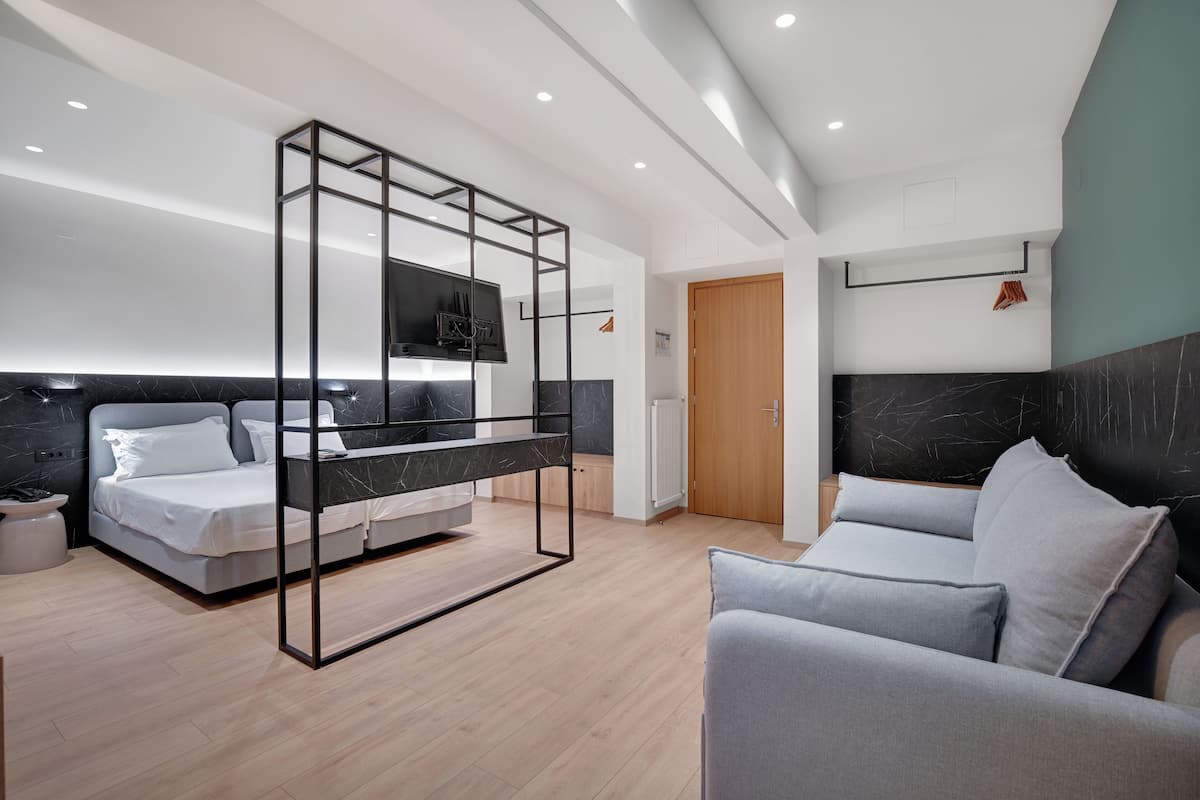 Een moderne hotelkamer met een bed, een bank, een televisie en een houten deur.