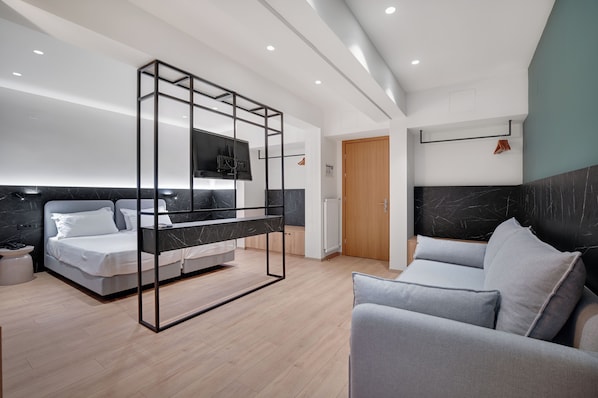 Una habitación de hotel moderna con una cama, un sofá, un televisor y una puerta de madera.