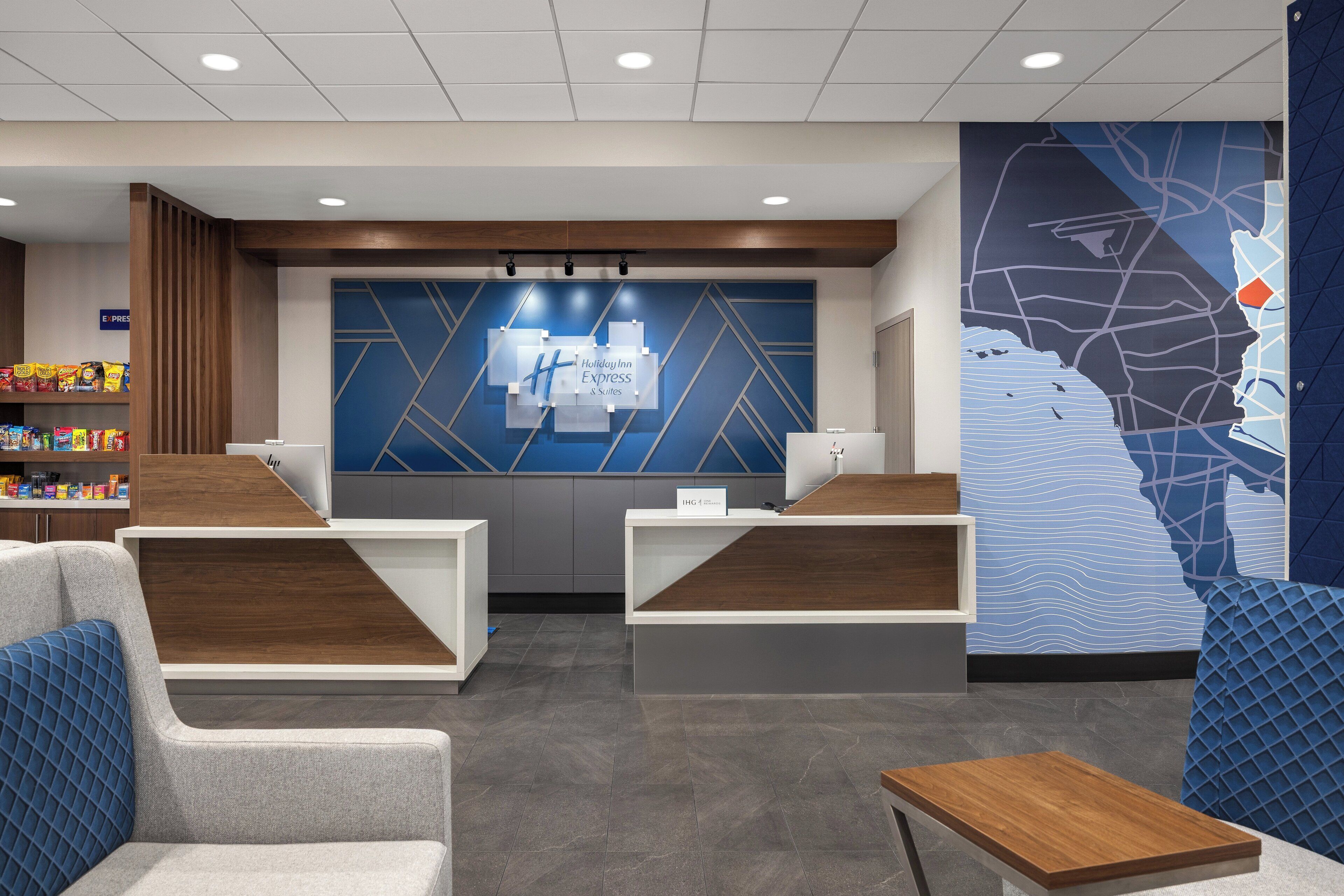 A Holiday Inn Express reception area with a modern design, including a reception desk, seating area, and a large wall map.