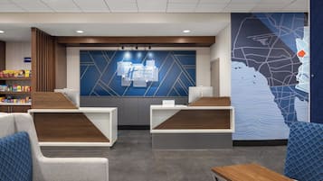 A Holiday Inn Express reception area with a modern design, including a reception desk, seating area, and a large wall map.