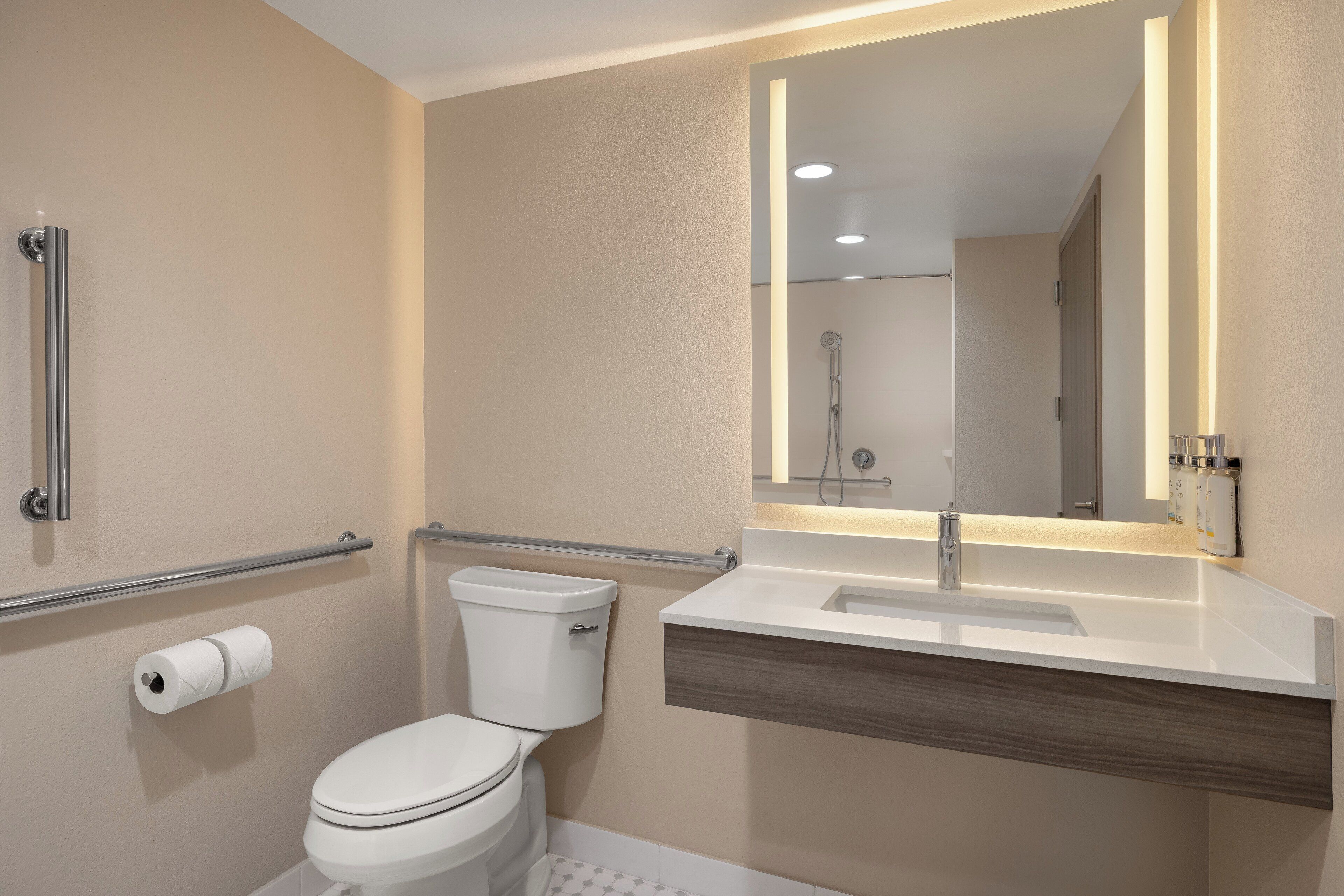 Un baño moderno con inodoro, lavamanos y espejo.