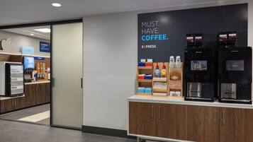 Una estación de café moderna con máquinas de café de la marca y un cartel que dice "NECESARIO. CAFÉ."