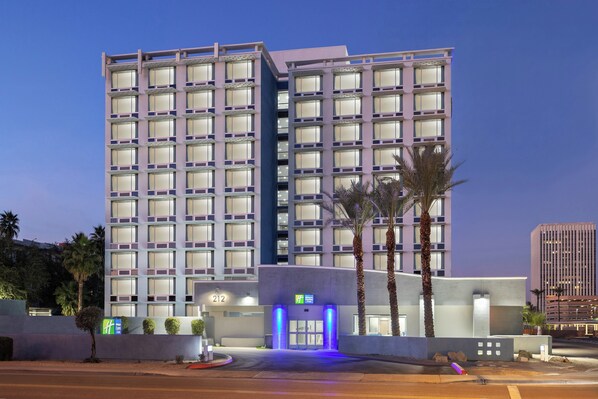A multi-story hotel with a modern facade, featuring a prominent entrance with illuminated signage. - Holiday Inn Express & Suites Phoenix Midtown by IHG (Phoenix)