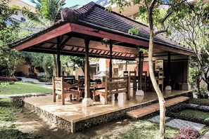 A covered outdoor seating area with benches and a pergola structure. -  Melasti Kuta Beach Hotel and Spa (Kuta)