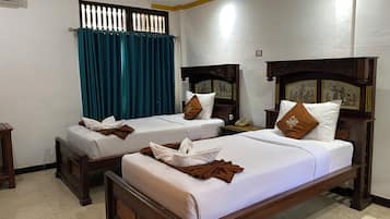 A hotel room with two beds, a window with curtains, a wall-mounted air conditioner, and a telephone on the nightstand.