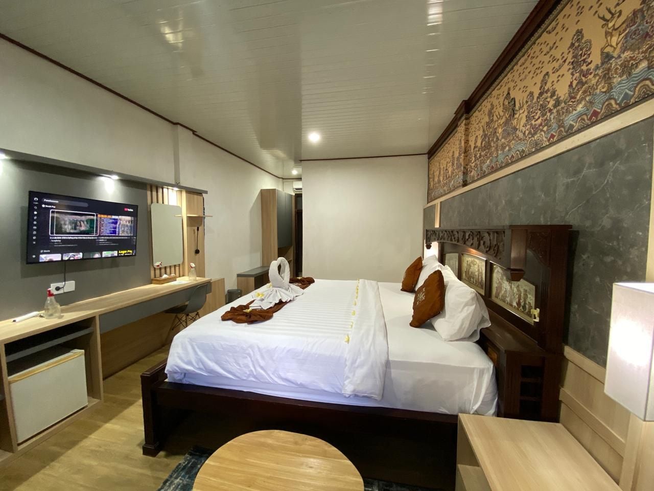 Una habitación de hotel con una cama, un escritorio, un televisor y una obra de arte colgada en la pared.