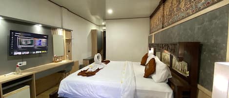 A hotel room with a bed, a desk, a television, and a wall-mounted artwork.