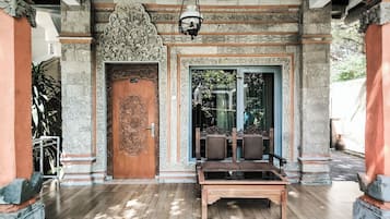 Una puerta de madera tradicional con intrincados grabados, un banco y una lámpara colgante.