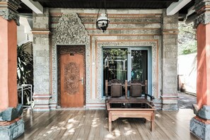 Una puerta de madera tradicional con intrincados grabados, un banco y una lámpara colgante.