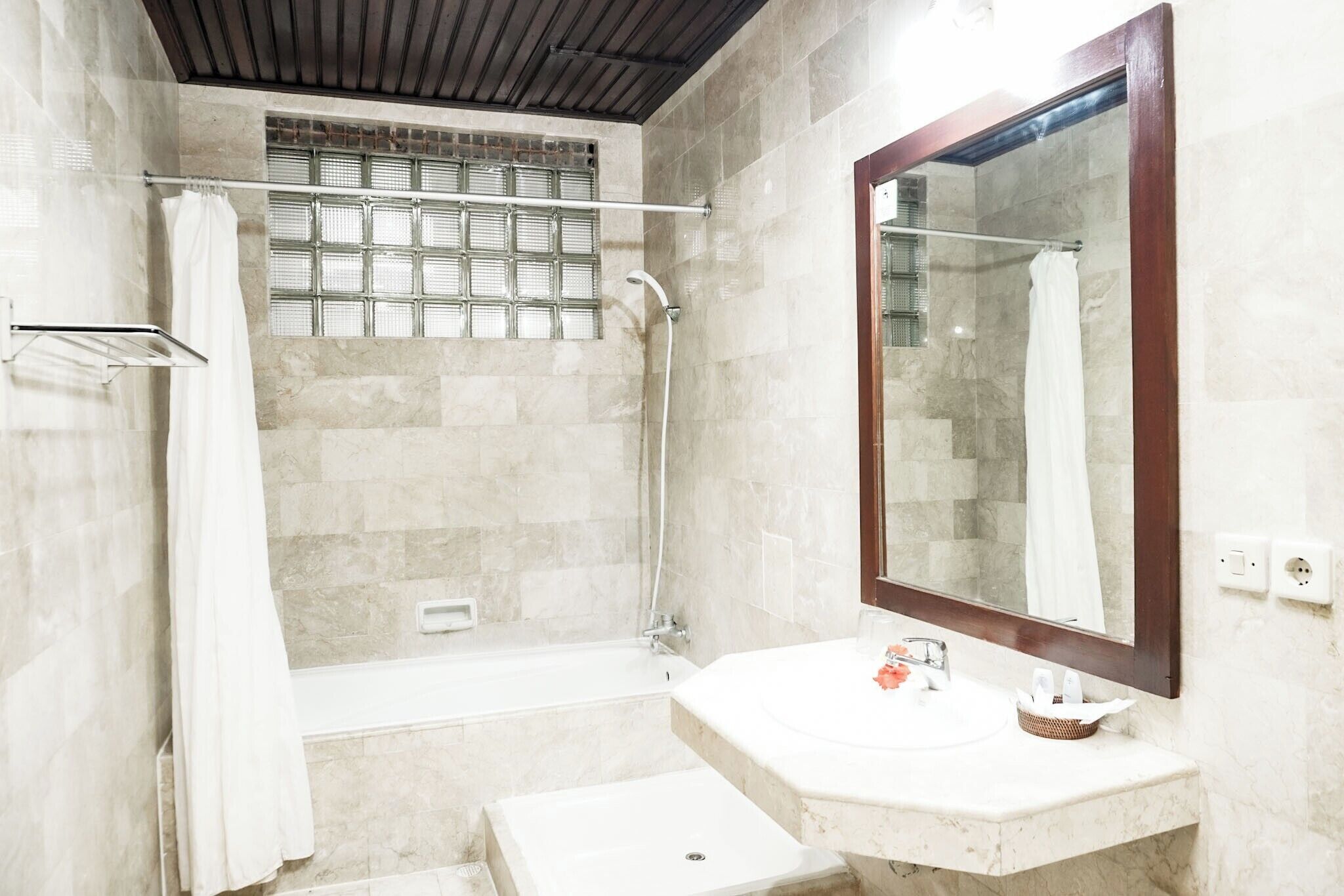 Une salle de bain équipée d’une douche, d’un lavabo, d’un miroir et d’un porte-serviettes.