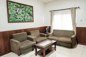 A living room with a sofa set, a coffee table, and a painting on the wall. - Melasti Kuta Beach Hotel and Spa (Kuta)