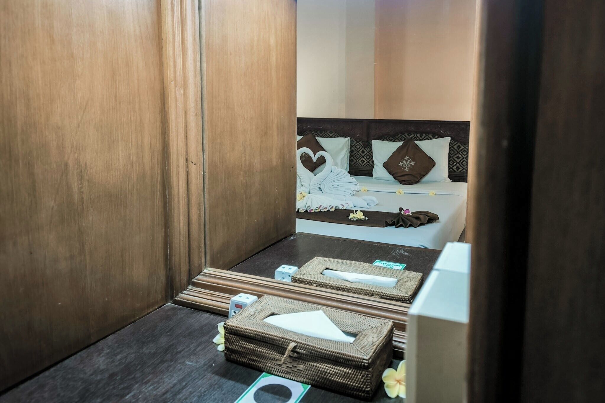 A small, compact room with a bed, a wooden wardrobe, and a small table with toiletries.